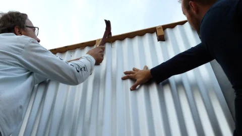 A crew of construction workers hammering and installing industrial metal Video stock 120755800