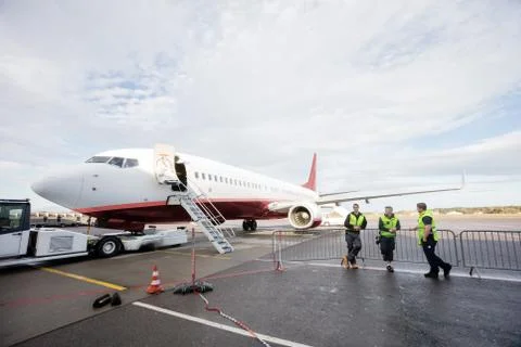 Crew Leaning On Fence While Standing By Airplane Stock Photos