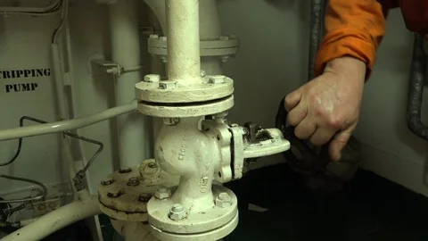 Crew member hand turns on pipe valve in tanker close view Stock Footage 121119662