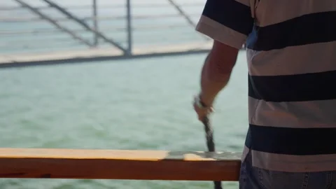 Crew member standing on boat deck on sunny day holding mooring rope Stock Footage 325451458