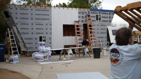 A crew of men construction workers building a tiny house on a job site for Video stock 120755687