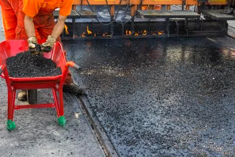 Crew placing mastic asphalt road and pea gravel surfacing Stock Photos