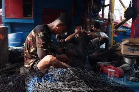 Crew repairs tangled net aboard fishing vessel in Jakarta Foto stock