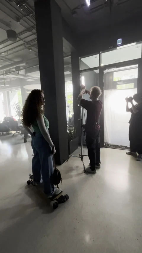 Crew sets up equipment in office while model rides skateboard for fun Stock-Footage 303060317