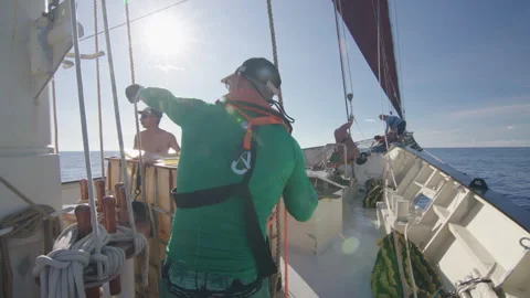 Crew work with the sails on the big expeditional sailing vessel moving in the Stock Footage 345684471