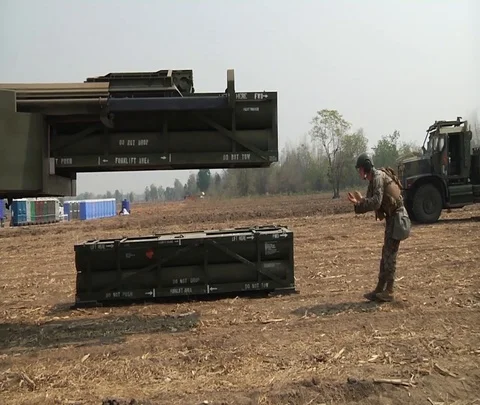 Crewman guiding high mobility artillery rocket system unloading ammunition Stockbeeldmateriaal 102944138