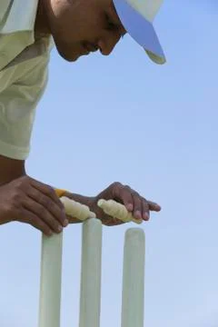 Cricket player adjusting bails on stumps Stock Photos