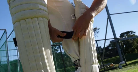Cricket player tying his batting pads during a practice session Stock Footage 78636904
