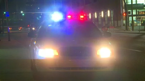 Crime and justice, police car, late night, lights flashing with traffic in bg Stock Footage