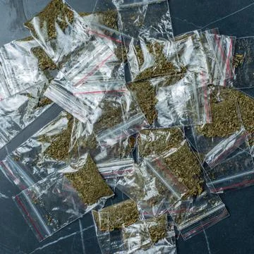Crime evidence: many packaged doses of cannabis lie on a dark surface. Foto stock