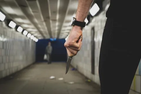 Crime robbery concept. A robber or a killer person with a sharp knife about to Stock Photos