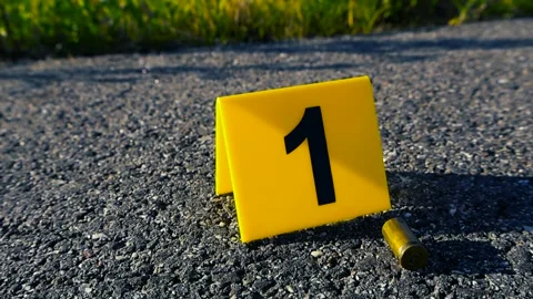 Crime scene evidence marker next to bullet casing on asphalt road Stock-Footage 337869887