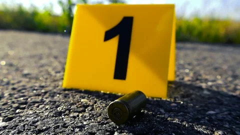Crime Scene Evidence Marker Next to a 9mm Bullet Casing, Bokeh Background Stock Footage 338993650