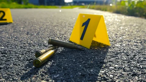 Crime Scene Evidence Markers Next to High Caliber Bullets on Asphalt Stock Footage 339770338