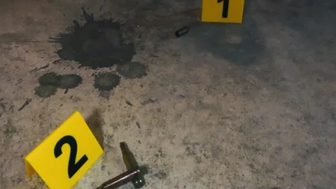 Crime scene evidence markers next to bullet casings on a concrete floor Stock Footage 346688374
