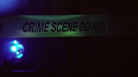 Crime Scene Police Tape with Flashing Beacon Lights of Car At Night Outside Stock Footage