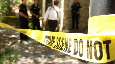 Crime scene tape with cops and a detectives in the background at a crime scene Stock Footage