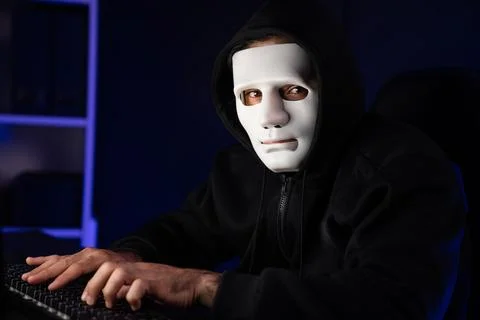 Criminal anonymous mask looking camera while install virus on keyboard. Surmise. 写真素材