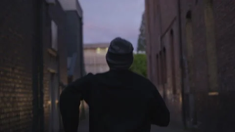 Criminal in a Beanie Running Through a Dark Alley Stock Footage 208727097