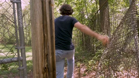 Criminal breaks into private property by going through a chain link fence Stock Footage 84629800