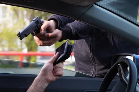 The criminal committed an armed robbery of the driver of the car. Stock Photos