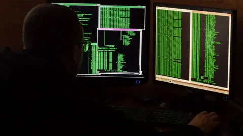 Criminal hacker penetrating network system from his dark hacker room. Rear view Stock Footage