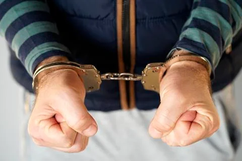 Criminal hands locked in handcuffs. Close-up view Stock Photos