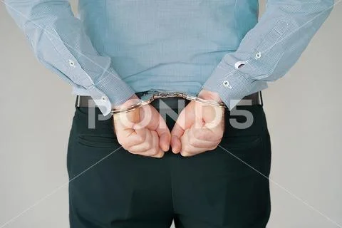 Criminal hands locked in handcuffs. Close-up view Stock Photos