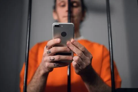 The criminal in the prison cell received a smartphone to communicate with Stock Photos