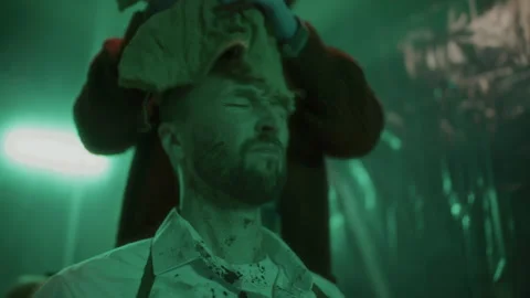 Criminal Removing Burlap Sack from Head of Bloodied Hostage in Dim Basement Stock Footage 301510714