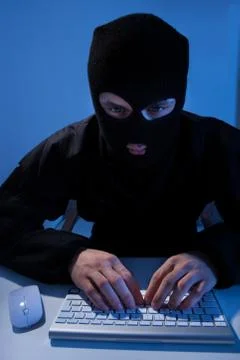 Criminal using computer to hack online account at table Stock Photos