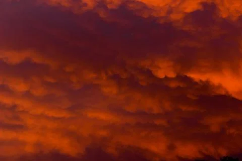 Crimson cloudy sky at sunset Stock Photos