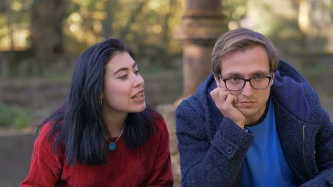 Crisis, break up. absent mind man not listening his angry wife in the park Stock Footage 112250385