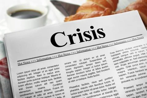 Crisis in newspaper layout on a breakfast table with a blurry cup of coffee.. Stock Photos