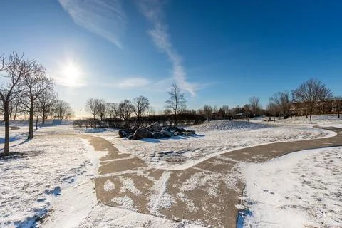 A crisp winter day in the park. Sunlight glints off the snow-dusted paths,.. 스톡 사진