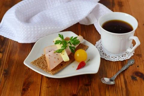 Crispbread, cheese, ham, cherry tomato, cup of coffee on a wooden background Stock Photos