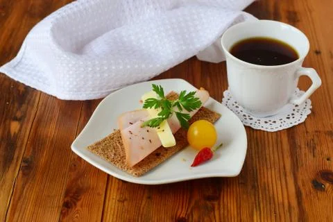 Crispbread, cheese, ham, cherry tomato, cup of coffee on a wooden background Stock Photos