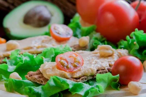 Crispbread with hummus on vegetable background Stock Photos
