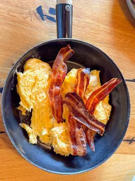 Crispy Bacon and Fluffy Scrambled Eggs in Skillet Fotos de archivo