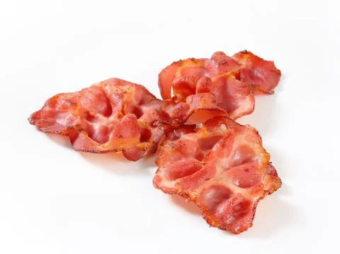 Crispy bacon pieces on white surface Stock Photos