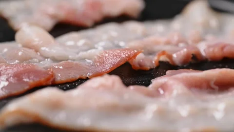 Crispy bacon sizzling in a pan, close-up shot. Stock Footage 317451376