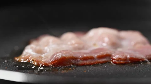 Crispy bacon sizzling in a pan, close-up shot. Vídeo Stock 317451547