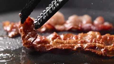 Crispy bacon sizzling in a pan, close-up shot. Stock Footage 317451973