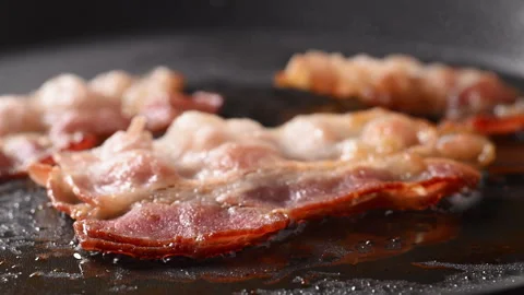 Crispy bacon sizzling in a pan, close-up shot. Stock Footage 317451979