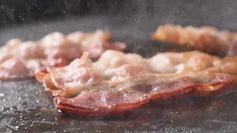 Crispy bacon sizzling in a pan, close-up shot. 動画素材 317452134