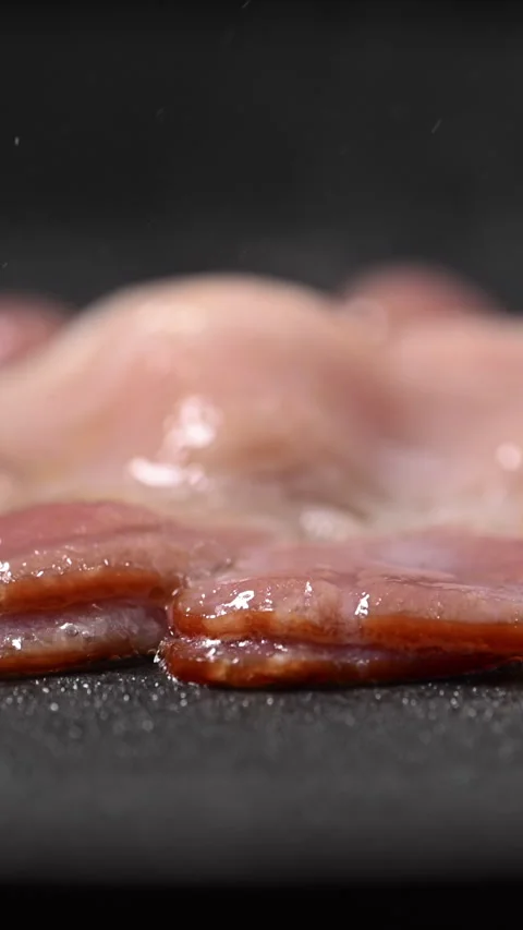 Crispy bacon sizzling in a pan, close-up shot. 動画素材 317452188