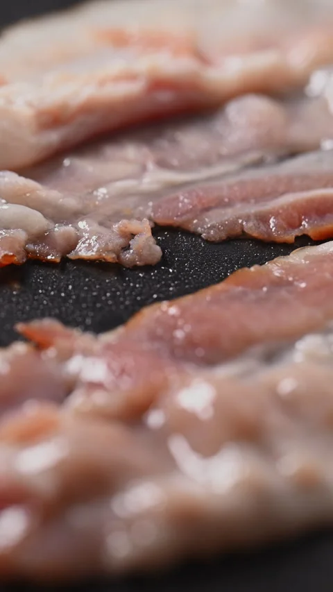 Crispy bacon sizzling in a pan, close-up shot. 動画素材 317452214