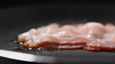 Crispy bacon sizzling in a pan, close-up shot. 動画素材 317452261