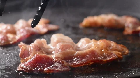Crispy bacon sizzling in a pan, close-up shot. 動画素材 317452454