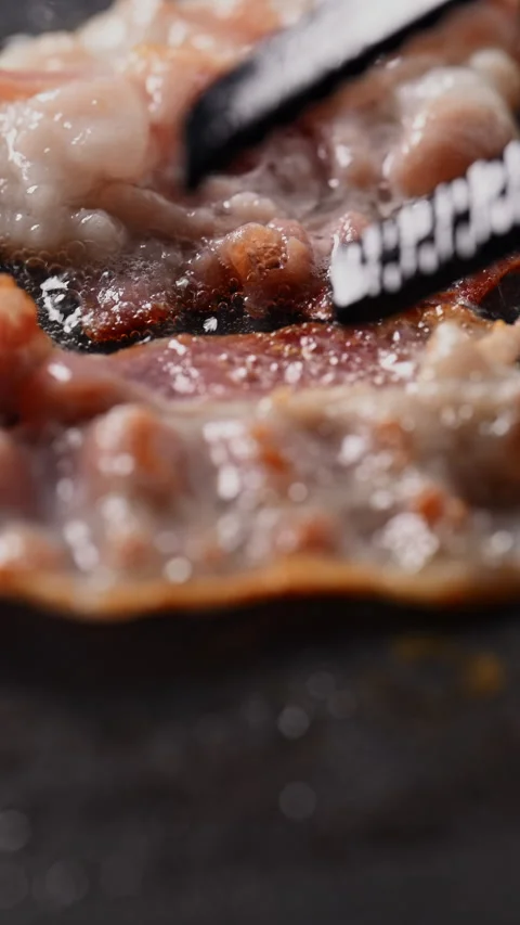 Crispy bacon sizzling in a pan, close-up shot. 動画素材 317452492